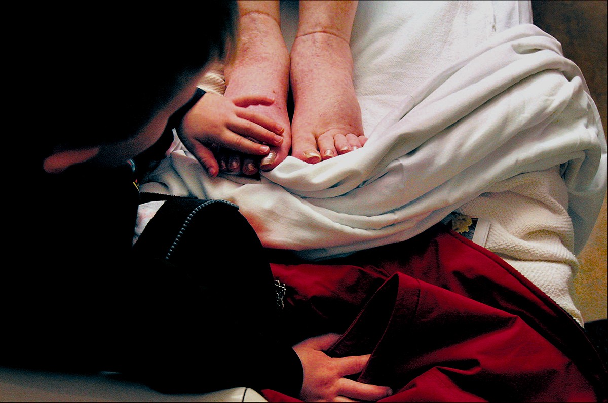 During a hospital visit, EJ touches Carolynne's swollen feet where Melissa had painted her toenails. Fluid build-up in her legs was one factor that forced Carolynne to stop chemotherapy. After a week in the hospital, she was sent home under hospice care. (1/13/07)