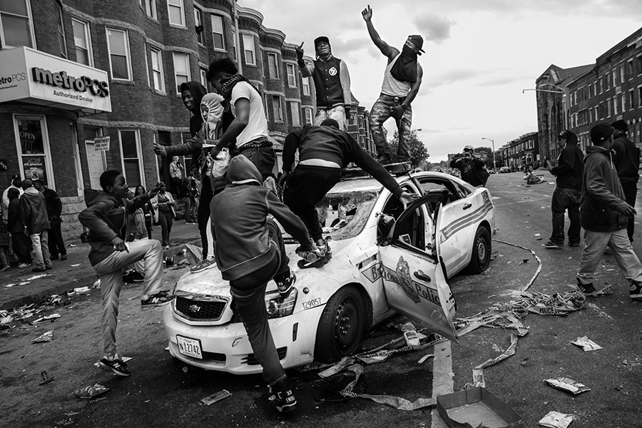 Demonstrators climb on a destroyed Baltimore Police car in the street near the corner of Pennsylvania and North avenues during violent protests following the funeral of Freddie Gray in Baltimore, Maryland. Gray, 25, who was arrested for possessing a switch blade knife April 12 outside the Gilmor Homes housing project on Baltimore's west side. According to his attorney, Gray died a week later in the hospital from a severe spinal cord injury he received while in police custody (Chip Somodevilla, Getty Images 