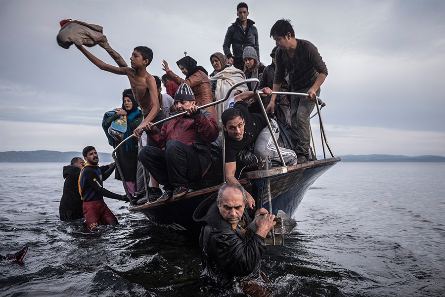 Migrants arrive by a Turkish boat near the village of Skala, on the Greek island of Lesbos. The Turkish boat owner delivered some 150 people to the Greek coast and tried to escape back to Turkey; he was arrested in Turkish waters (Sergey Ponomarev, The New York Times - November 16, 2015).