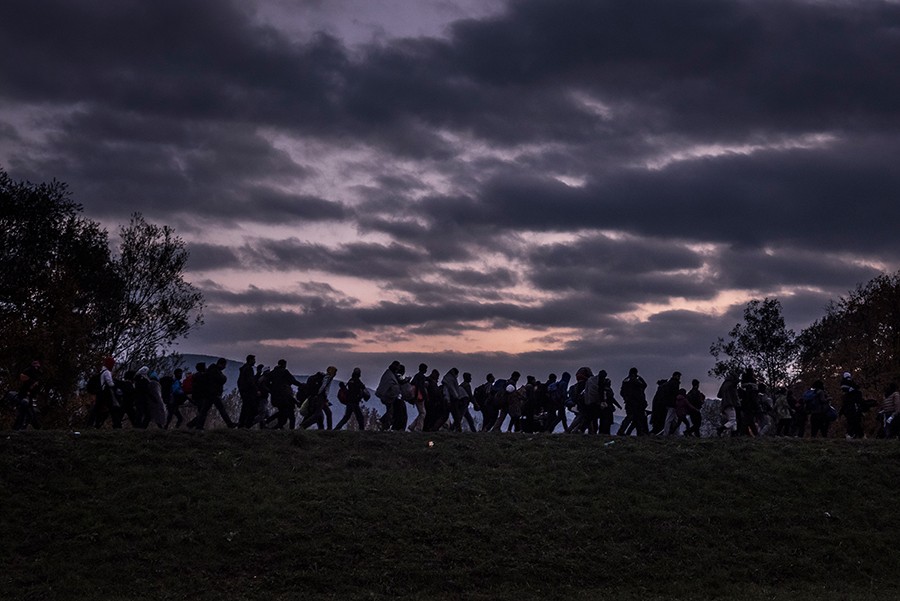 Migrants walking along a dike, escorted by Slovenian riot police, to a registration camp outside Dobova. Despite hopes that falling temperatures and treacherous seas would slow the tide of refugees, fresh fighting in Syria and growing fears of border closings drove more people to undertake the treacherous trek (Sergey Ponomarev, The New York Times - October 23, 2015).