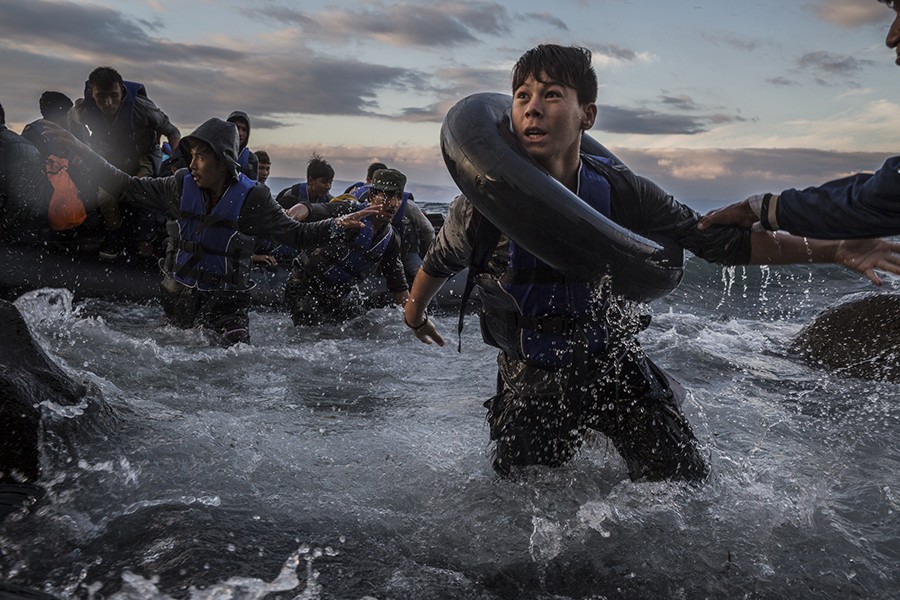 After battling rough seas and high winds from Turkey, migrants arrive by rubber raft on a jagged shoreline of the Greek island of Lesbos. Fearing capsize or puncture, some panicked and jumped into the cold water in desperation to reach land. This young boy made it, unlike hundreds of others (Tyler Hicks, The New York Times - October 1, 2015). 