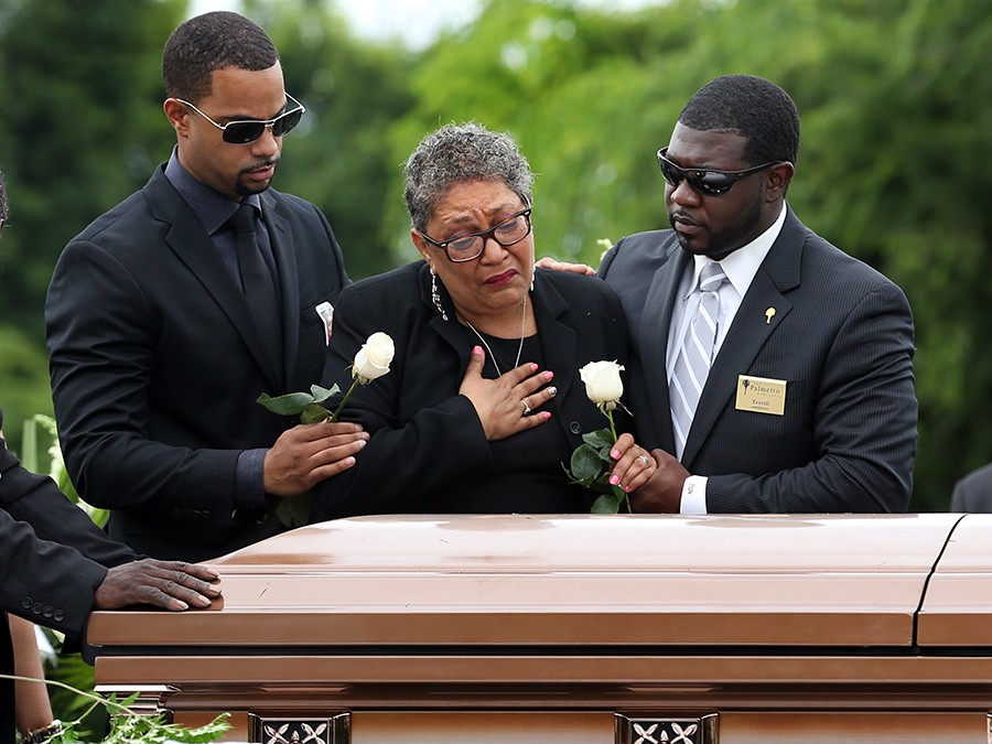 The family of Ethel Lance, one of the nine victims killed at Emanuel AME Church, surround her casket to say their final goodbye. Her grandson, Howard Risher, left and her daughter, the Rev. Sharon Risher, place roses on the casket before it is lowered into the ground (Grace Beahm, The Post and Courier - on Thursday, June 25, 2015).