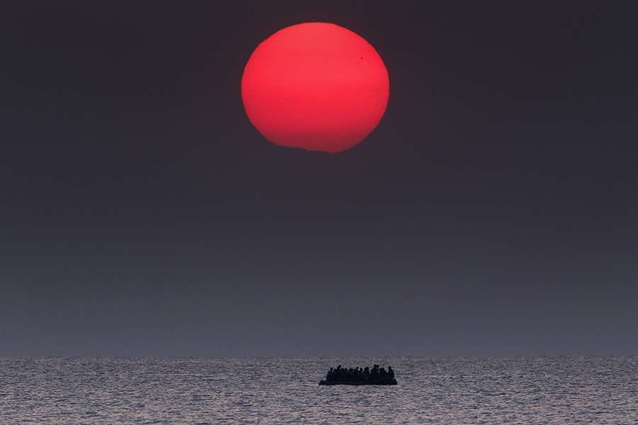 A overcrowded inflatable boat with Syrian refugees drifts in the Aegean sea between Turkey and Greece after its motor broke down off the Greek island of Kos. In 2015 over a million people sought asylum in Europe after departing their war torn and strife addled countries. They crossed in haphazard boats and inflatable dinghies with hundreds perishing at sea (Yannis Behrakis, Thomson Reuters - August 11, 2015).
