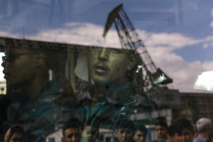 An Afghan migrant is seen inside a bus following his arrival by the Eleftherios Venizelos passenger ferry with over 2,500 migrants and refugees from the island of Lesbos at the port of Piraeus, near Athens, Greece (Yannis Behrakis, Thomson Reuters - October 8, 2015).