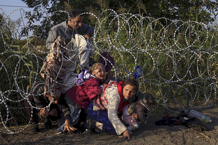 Syrian migrants cross under a fence as they enter Hungary at the border with Serbia, near Roszke (Bernadett Szabo, Thomson Reuters - August 27, 2015). 