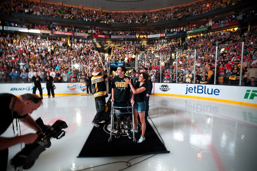 Invited by the Boston Bruins to appear before Game 6 of the Stanley Cup finals, Bauman stood and took a few steps, accompanied by his outpatient physical therapist, Michelle Kerr. At left, in the cowboy hat, is Carlos Arredondo, a bystander who helped Bauman shortly after the bombs detonated. Jeff did not want to appear, but his mother encouraged him and eventually convinced him, saying, 'this country needs some hope right now.' (Josh Haner, The New York Times - June 24, 2013)