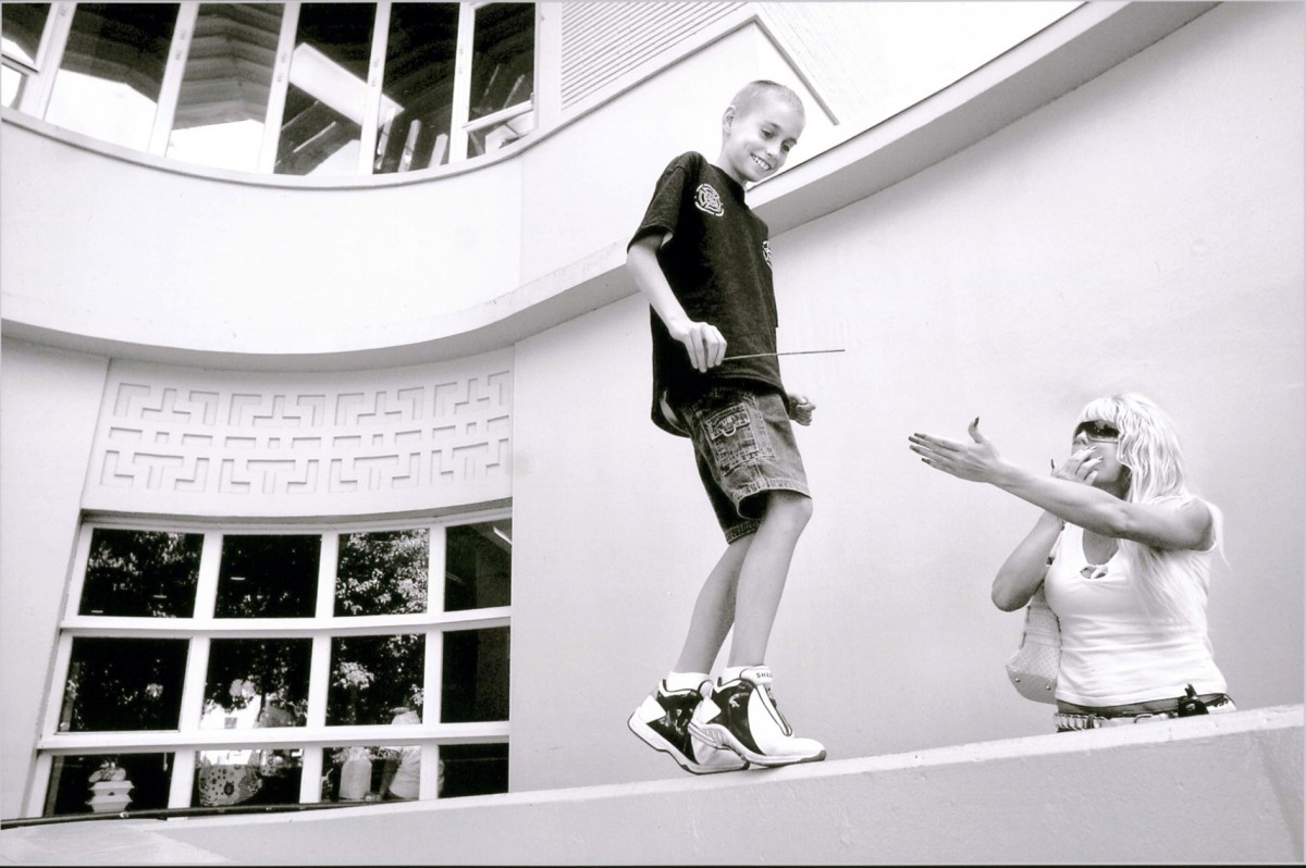 Derek playfully taunts his mother as Cyndie tries to coax him down from a wall outside the UC Davis Medical Center in Sacramento. They are there to admit Derek for cancer surgery the following day. Cyndia, who understands Derek's emotional meltdown before procedures, spends hours getting him in the door of the hospital.