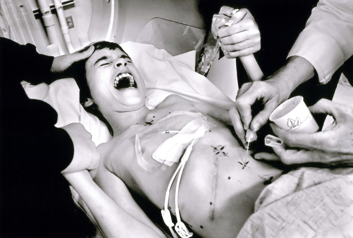 Shortly after his 11th birthday and Cyndie's 40th, Derek is comforted by his brother Micah Moffe, 17, left, and mom Cyndie, right, as he gets a tattoo in preparation for radiation therapy on November 30, 2005. Micah often accompanies Derek to treatments even though his schoolwork suffers.