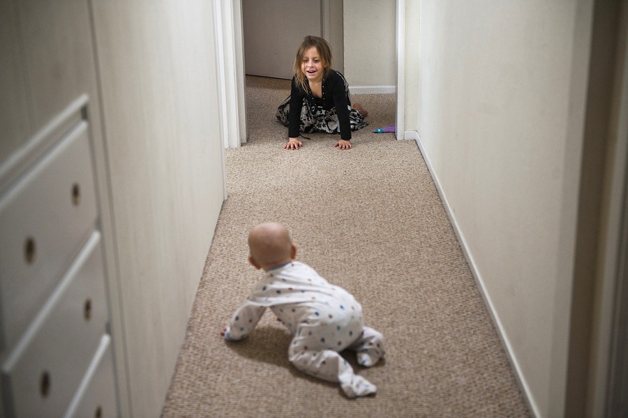 Eva, 4, cheers her brother Alex, 10 months, as he learns how to crawl in the hallway of their new home in Napa. (April 6, 2012)