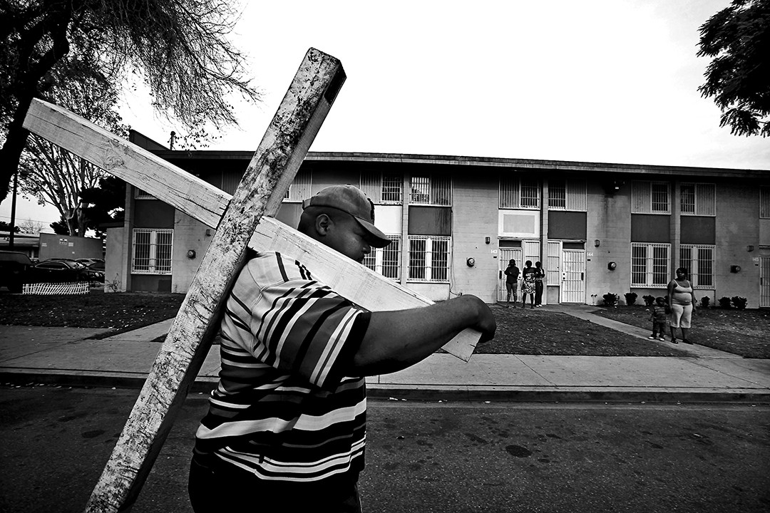 Pastor Wyman Jones of Sweet Hill Baptist Church in South Los Angeles carries a wooden cross through the Nickerson Gardens public housing complex to protest gang violence. Nickerson Gardens had seen a sustained lull in violence, but in 2009 and 2010 the area erupted once again, claiming the lives of at least six men. Police have said the violence was linked to a civil war of sorts within the Bounty Hunters, for years the dominant gang in Nickerson Gardens, apparently over drug sales.  (Barbara Davidson, Los 