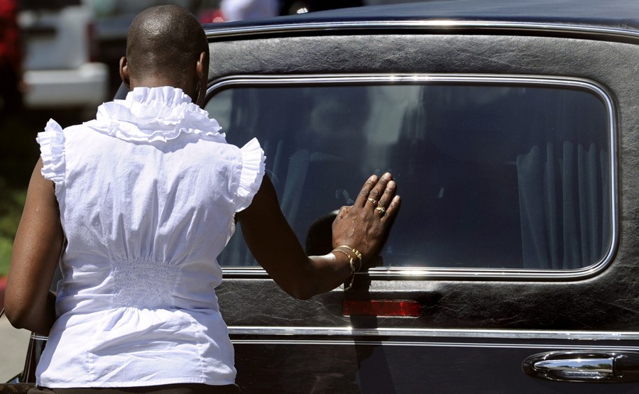 With the casket of AJ Boik already placed inside, a woman pauses and places her hand on the back window of the hearse. (Kathryn Scott Osler - July 27, 2012)