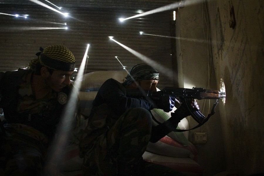 Two rebel soldiers in Syria guard their position in the Karmel Jabl neighborhood of Aleppo as light streams through more than a dozen holes made by bullets and shrapnel in the tin wall behind them. The dust from more than one hundred days of shelling, bombing and firefights hung in the air. Karmel Jabl is strategically important because of its proximity to the main road that separates several of the main battlegrounds in the city. (Photo taken October 18, 2012)