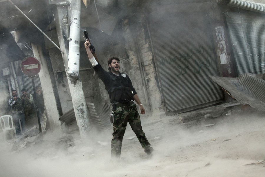 A rebel fighter gestures for victory after firing a shoulder-fired missile toward a building where Syrian troops loyal to President Bashar Assad were hiding as they attempted to gain terrain against the rebels during heavy clashes in the Jedida district of Aleppo, Syria, Nov. 4, 2012. (Narciso Contreras, Associated Press- November 4, 2012)