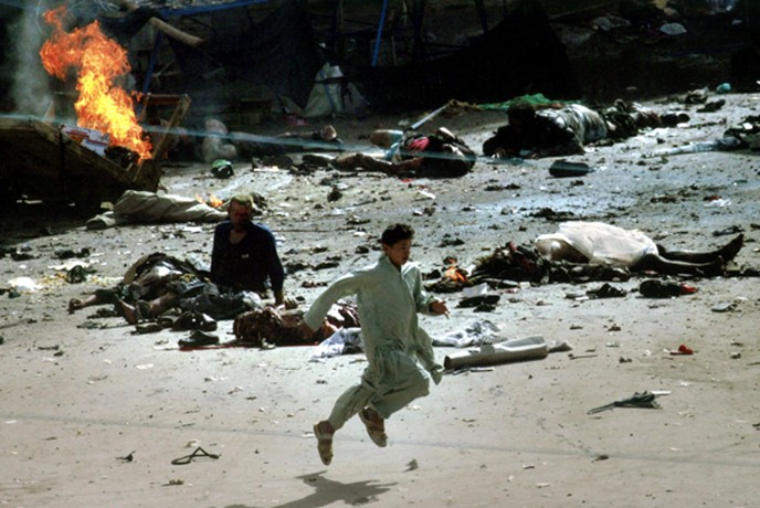 Karbala - Moments after a series of bomb blasts on the Muslim day of Ashoura, a youth runs past victims and debris in a busy area of the holy city. 