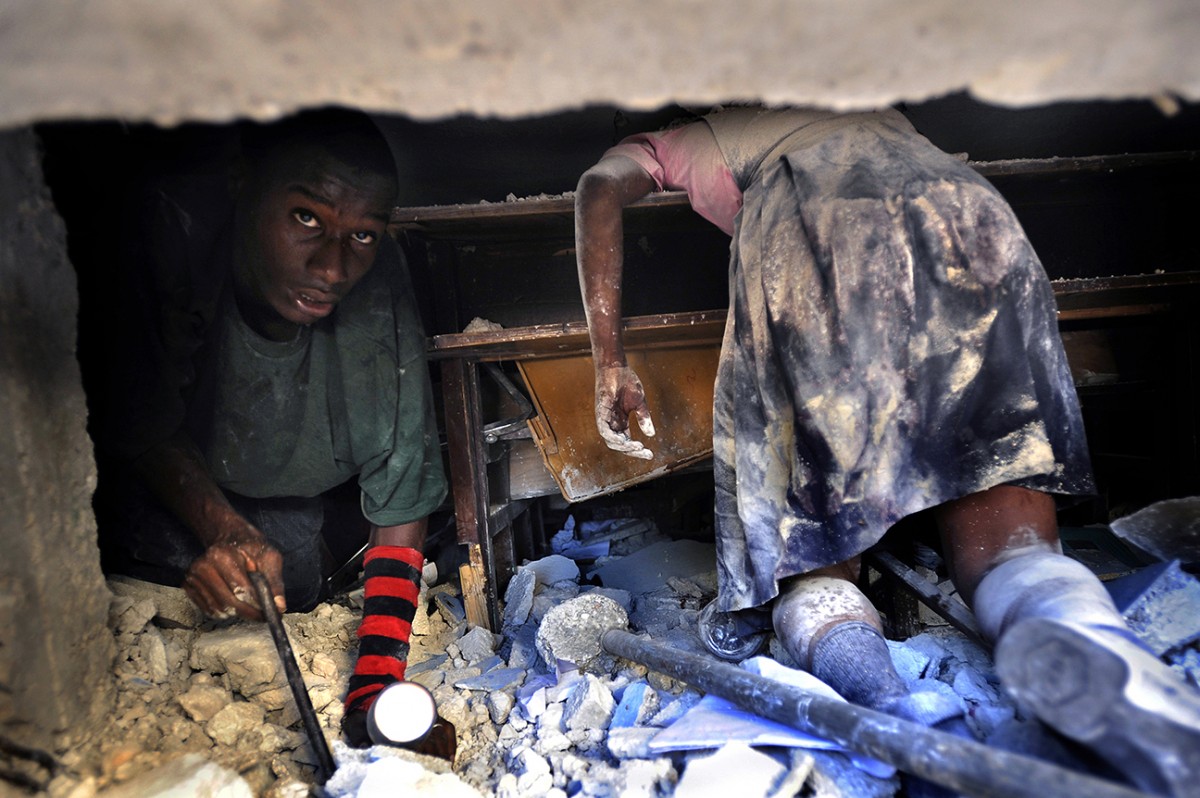 'Death of Innocence'  A Haitian man tries to rescue a live teacher trapped amid the rubble of the devastating earthquake in Port-au-Prince as he crawls past a schoolgirl that perished at her desk when Ecole St. Gerard collapsed. (Carol Guzy, The Washington Post - January 15, 2010 )