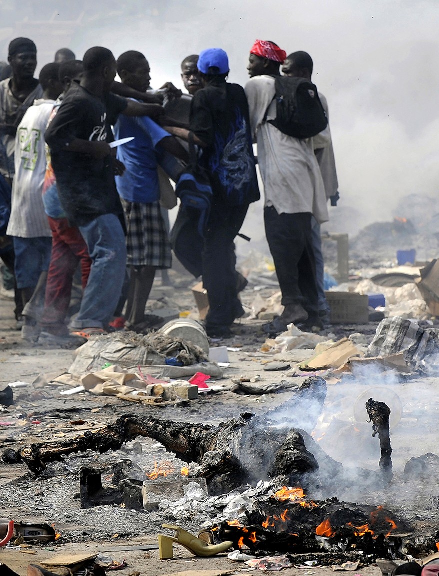 'Burn'  The smell of charred flesh lingers as Haitian survivors burn bodies and brandish knives while taking goods from stores in the market. Disorder erupted after the earthquake left Port-au-Prince in ruins. Security emerged as one of the most formidable challenges in the earthquake-shattered capital, limiting the ability of the United Nations and relief officials from elsewhere to distribute food and medicine. (Carol Guzy, The Washington Post - January 18, 2010)